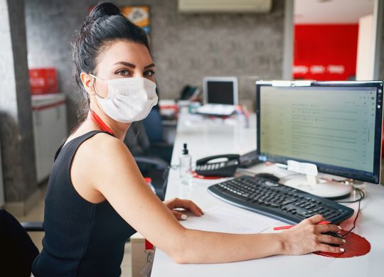 Businesspeople wearing masks in the office and working on bigger distance for safety during COVID-19 pandemic